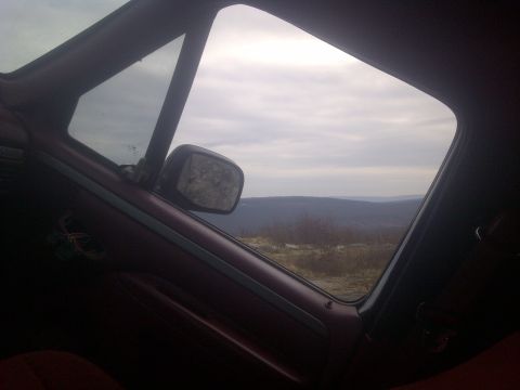 1995 Ford Bronco - View from inside a vehicle, looking out at a vast, hilly landscape under an overcast sky.