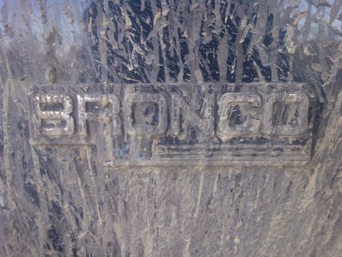 1995 Ford Bronco - The "BRONCO" emblem is clearly visible despite being covered in mud.