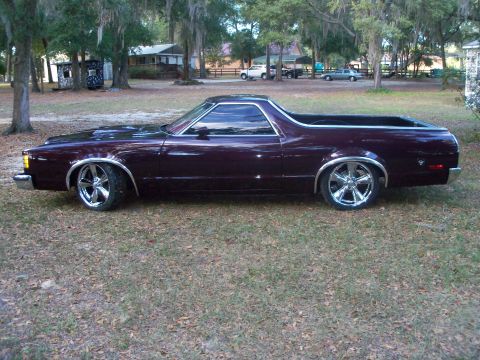 1979 Ford Ranchero - Full driver-side profile of a lowered dark purple-maroon Ford coupe-utility with deep gloss paint, tinted glass, chrome trim and large poli…