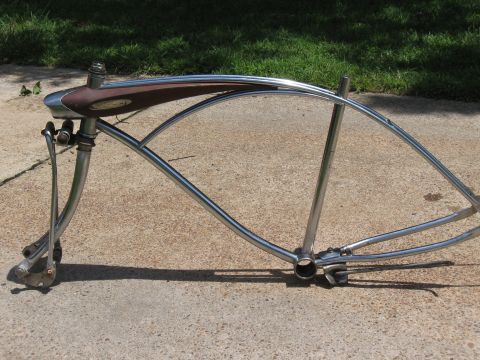 1994 Ford Bronco - A bicycle frame with chrome tubing and a brown saddle mount is displayed outdoors on a concrete surface.