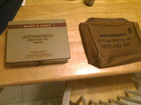 2003 Ford Crown Victoria - A Bauer & Black Automobile First Aid Kit No. 40 in a metal tin sits next to a similar kit in a canvas bag.