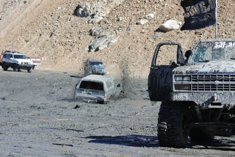 1978 Ford Bronco - Several off-road vehicles are stuck in thick mud, kicking up spray as they try to navigate the terrain.