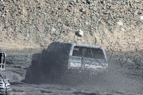 1978 Ford Bronco - 1978 Ford Bronco navigates a challenging mud pit, sending thick spray into the air.