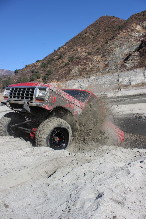 1978 Ford Bronco - Red 1978 Ford Bronco navigating a muddy terrain, getting stuck.