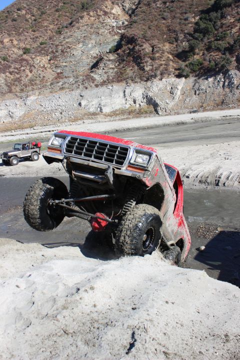1978 Ford Bronco - This heavily modified truck navigates a challenging off-road course with one wheel lifted high.