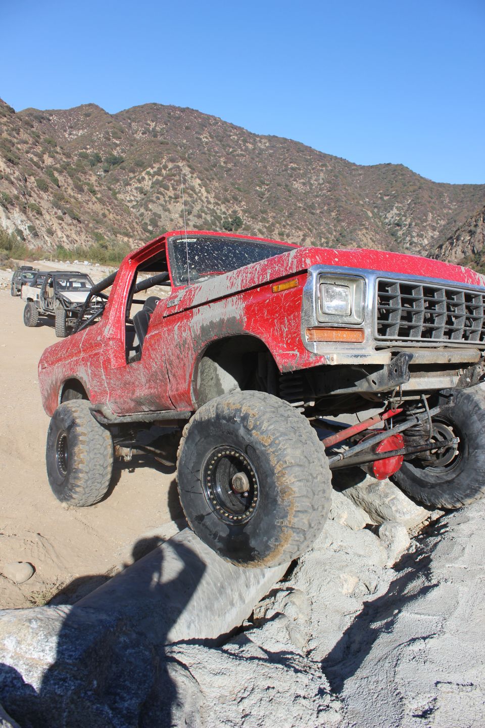 Red 1978 Ford Bronco climbing rocks with large tires