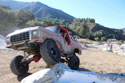 1978 Ford Bronco - A heavily modified truck navigates a rocky obstacle course on a sunny day.