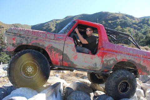 1978 Ford Bronco - Mud-covered 1978 Ford Bronco with roll cage tackling rocky terrain.