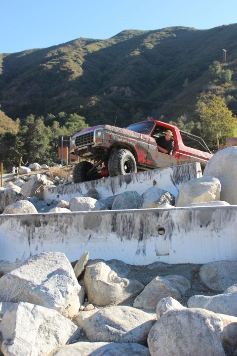 1978 Ford Bronco - A red truck navigates a rocky obstacle course with a driver behind the wheel.