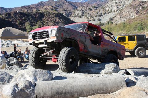 1978 Ford Bronco - Red 1978 Ford Bronco navigates a rocky obstacle course with a yellow Jeep nearby.