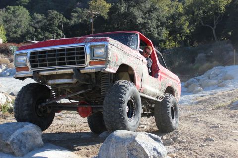 1978 Ford Bronco - This red 1978 Ford Bronco navigates a rocky trail with its driver visible.