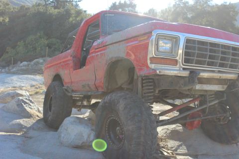 1978 Ford Bronco - This lifted 1978 Ford Bronco is navigating a rocky terrain with its large off-road tires.