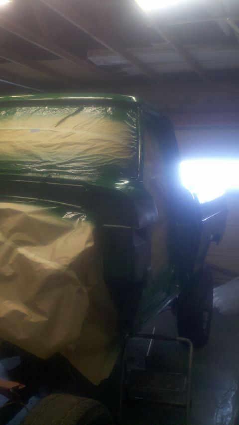 1967 Ford F-250 - A pickup truck is being painted green inside a garage, with masking tape covering parts of the body.