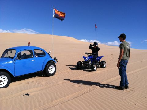 1970 Volkswagen Beetle - A blue Volkswagen Beetle and a blue ATV are parked in the sand dunes under a clear blue sky.