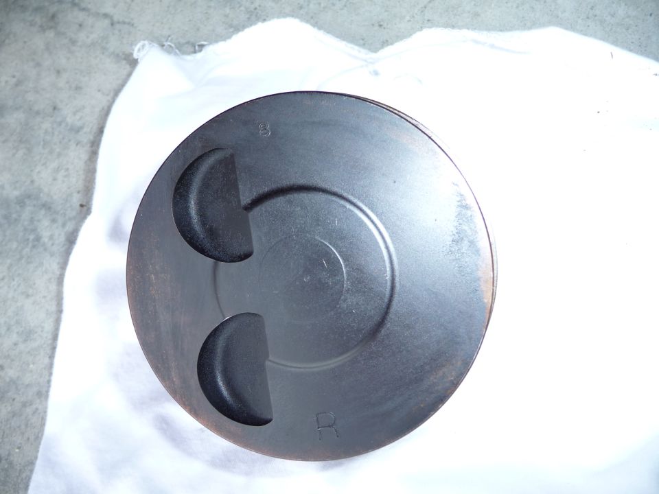 Engine piston with two valve reliefs and circular markings. 'B' and 'R' are visible