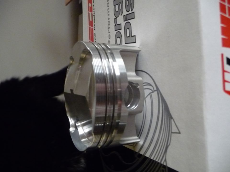 Close-up of a shiny metal piston with rings, next to a box with text