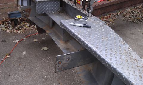 1979 Ford Bronco - A section of a metal ramp with diamond plate texture is shown, a tape measure and marker on its surface.