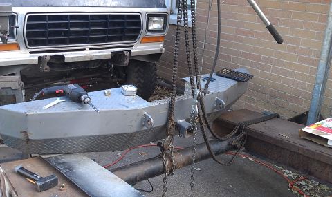 1979 Ford Bronco - Front view of a 1979 Ford Bronco's grille and bumper, with a drill and chains nearby.