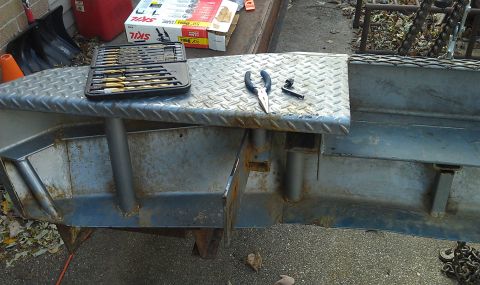 1979 Ford Bronco - Tools are laid out on a metal plow attachment, possibly for repair or modification.