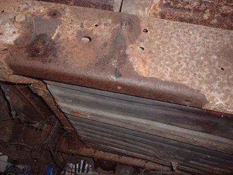 1993 Ford Bronco - Close-up view of a heavily rusted vehicle frame, showing structural components and wiring.