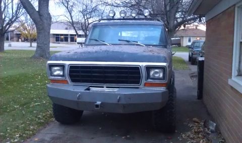 1979 Ford Bronco - A dark blue 1978 Ford Bronco with an aftermarket bumper and roof lights is parked in a driveway next to a brick building.