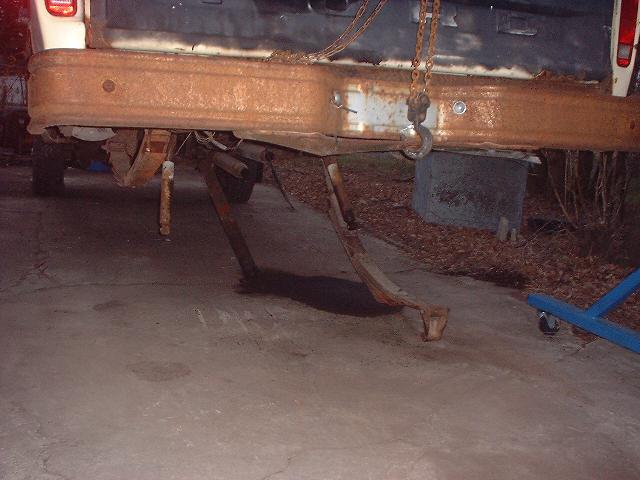 rusted rear bumper and suspension parts of a truck being worked on