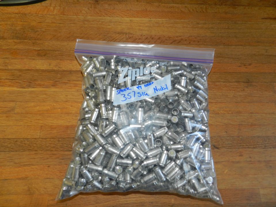 Bag of spent 357 SIG nickel casings on a wooden surface. Label reads 'Speer 1000+ 357 SIG Nickel'