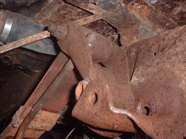 Rusted suspension components and exhaust pipe on a vehicle undercarriage