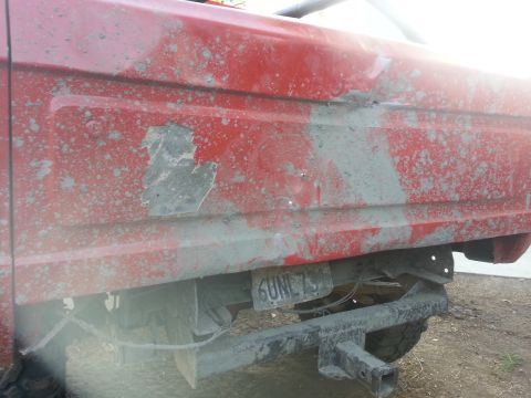 1978 Ford Bronco - Mud-splattered red SUV rear quarter panel with a visible license plate.