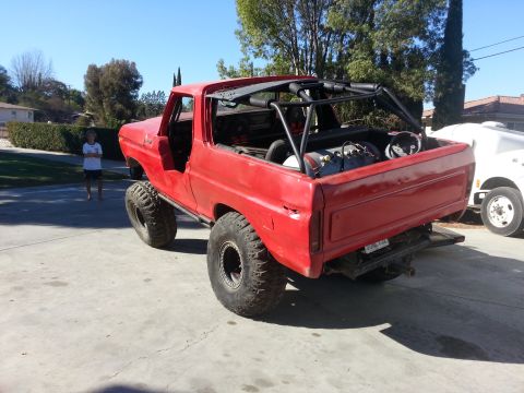 1978 Ford Bronco - This modified 1978 Ford Bronco features a prominent roll cage and oversized off-road tires, viewed from the rear.