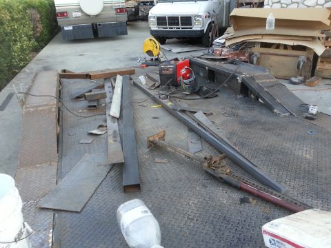 1978 Ford Bronco - Metal fabrication supplies and equipment are laid out on a trailer bed, with a truck and RV visible in the background.