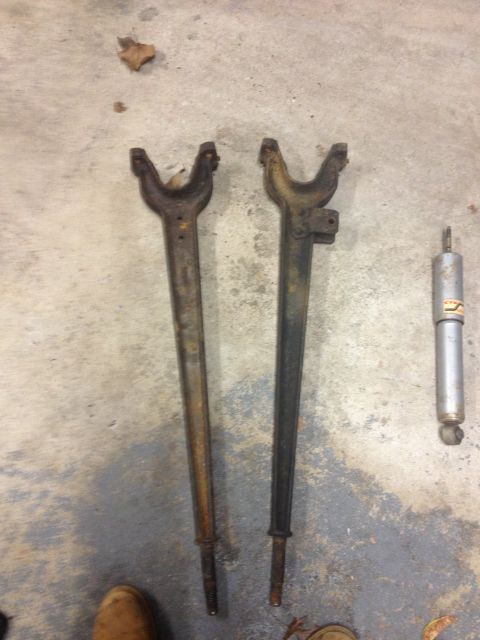 1996 Ford F-150 - Automotive suspension components, including two control arms and a shock absorber, are displayed on a concrete surface.