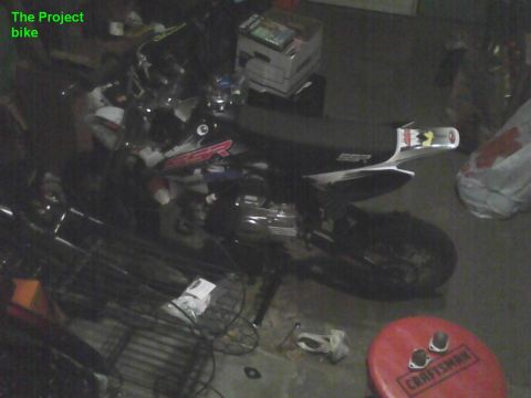 2003 Ford Crown Victoria - A motorcycle is parked in a cluttered garage space.