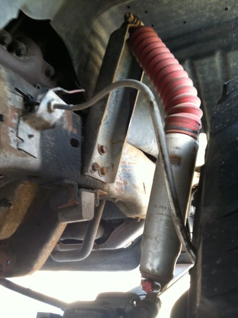 1997 Ford F-250 - Close-up of a shock absorber with a red boot, showing a "1999" marking on the cylinder.
