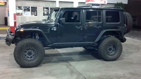 2008 Jeep Wrangler - A black Jeep Wrangler is parked at a gas station, showing its modified suspension and off-road tires.