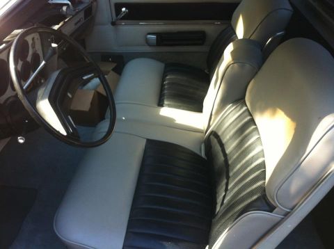 1979 Ford Ranchero - The interior of a vehicle shows light-colored seats with black inserts and a dark steering wheel.