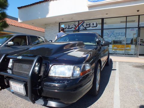 2003 Ford Crown Victoria - Front quarter of a black Crown Victoria sedan with a black grille guard, primer note on bumper, outside Maxco Paint and Body