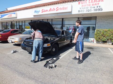 2003 Ford Crown Victoria - Crown Victoria undergoing front-end work at Tony's Siam Auto Services, hood up and bumper cover lying on the lot