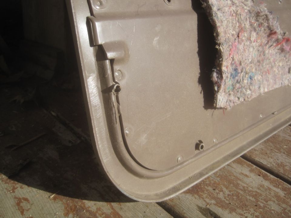 Close-up of a tan vehicle door panel with insulation visible