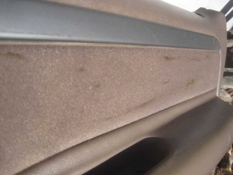 Close-up of a tan car door panel with a horizontal silver trim piece