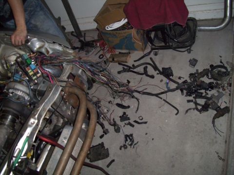1995 Ford Probe - A disassembled vehicle wiring harness and engine parts are laid out on a concrete floor.