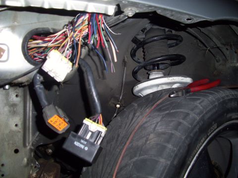 1995 Ford Probe - Exposed wiring harness and suspension components in a vehicle, with a tire and pliers in view.