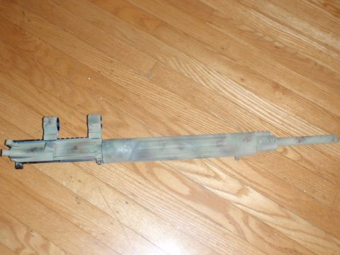 2000 Dodge 1500 - A rifle barrel assembly with a camouflage paint scheme is displayed on a wooden floor.
