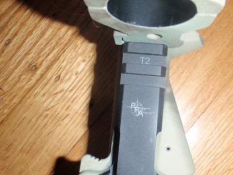 2000 Dodge 1500 - Close-up of a gun part with T2 marking and RRA logo on a wooden surface.