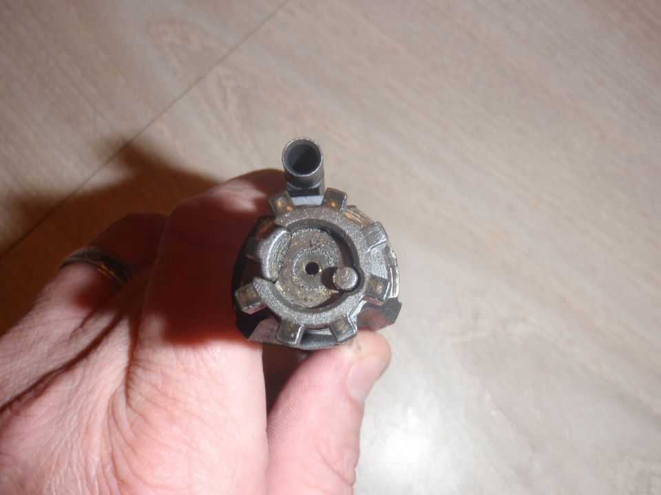 Metal part with gear-like teeth and a central hole, held by a hand