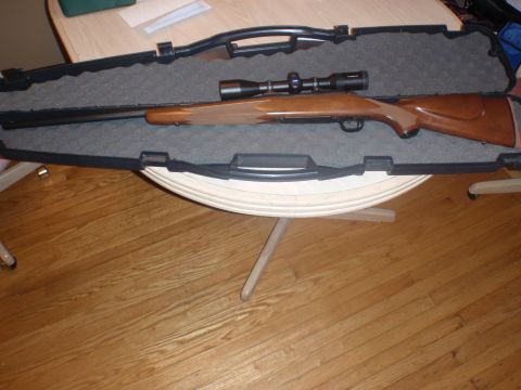 2000 Dodge 1500 - A rifle with a scope is displayed inside its protective case, resting on a table.
