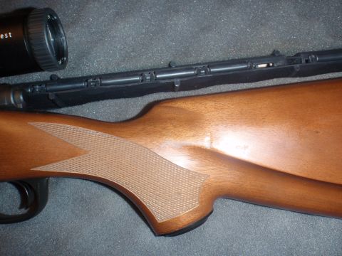 2000 Dodge 1500 - A rifle with a wooden stock and a scope is shown in this close-up view.