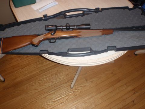 2000 Dodge 1500 - A rifle with a scope is displayed inside its protective gun case, resting on a table.