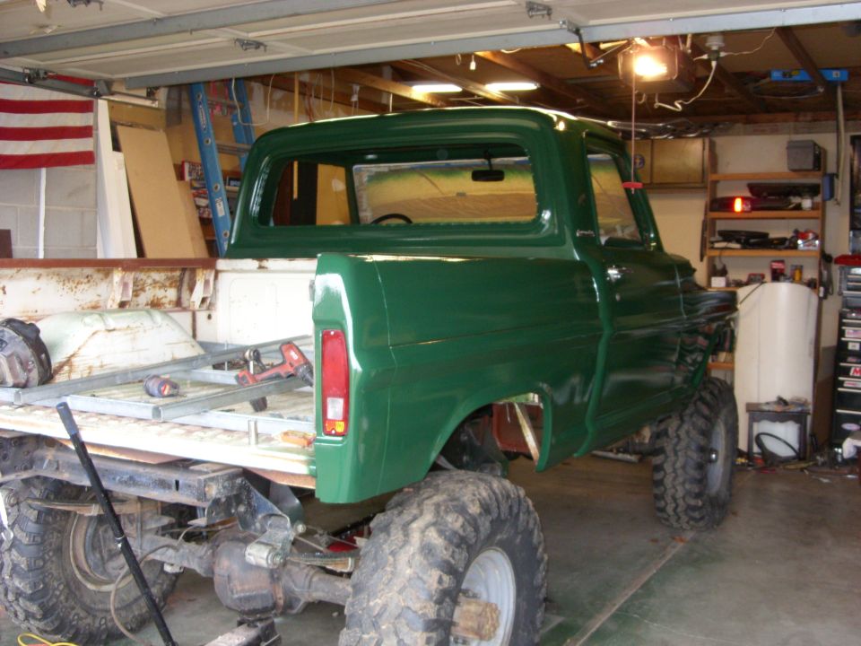 Green 1967 Ford F-250 pickup truck with large tires, in a garage