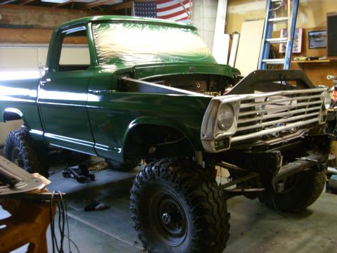 1967 Ford F-250 - A green 1967 Ford F-250 pickup truck is shown in a garage with its hood open and lifted suspension.